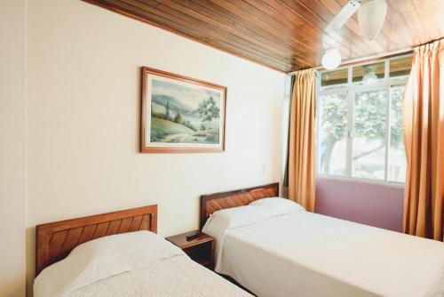 1 dormitorio con 2 camas y ventana en Flamboyant Hotel, en Barra Velha