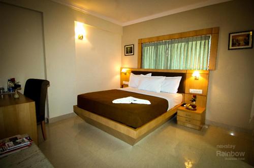 a hotel room with a bed and a window at New Rainbow Business Hotel in Bengaluru