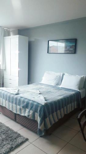a bedroom with a bed with a blue wall at Pousada Loft Praia dos Anjos in Arraial do Cabo