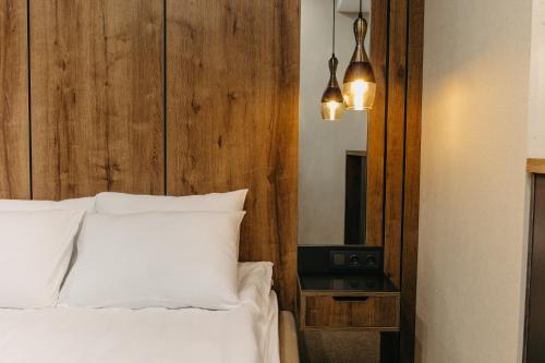 1 dormitorio con cama blanca y cabecero de madera en Hotel Sky Station en Tiflis
