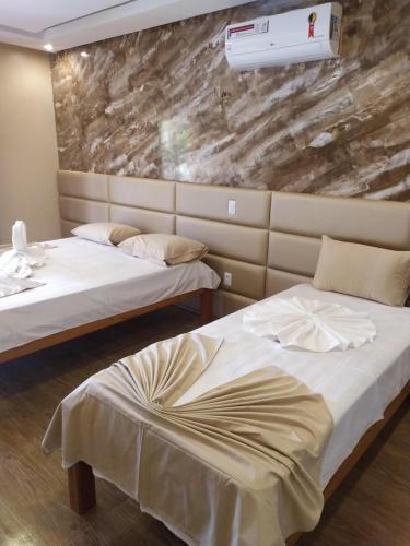 duas camas num quarto com uma parede de pedra em Pousada e Restaurante Lagoa Azul em Jijoca de Jericoacoara