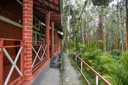 a red brick building with a porch and trees at Coffee Grove Resort in Chikmagalūr