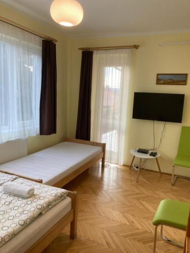 a room with two beds and a flat screen tv at Kurca-parti Vendégház in Szentes