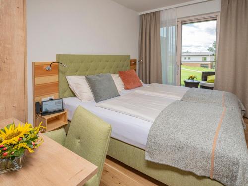 Schlafzimmer mit einem Bett, einem Tisch und einem Fenster in der Unterkunft Hotel Ottenstein - Das Wohlfühlhotel in Rastenfeld