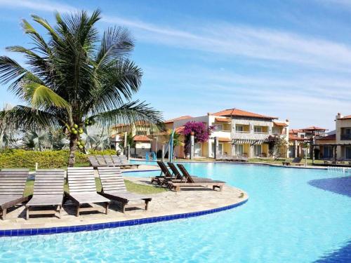 una piscina con sedie a sdraio e palme di Búzios Beach Resort Luxo a Búzios