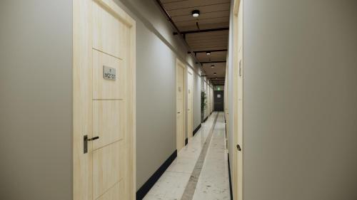 a corridor with wooden doors and a hallway with white walls at Maine City Residences Leveriza in Manila