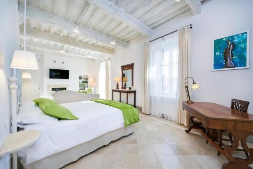 ein weißes Schlafzimmer mit einem Bett und einem Holzschreibtisch in der Unterkunft Palazzo Pio III - Residenza d'epoca in Sarteano