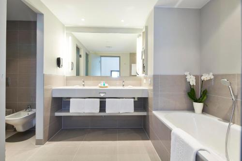 a bathroom with a tub and a sink and a bath tubermott at Steigenberger Hotel Am Kanzleramt in Berlin