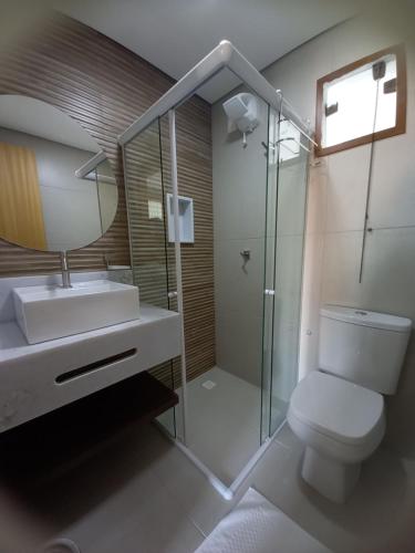 Un baño con inodoro, lavabo y espejo. en Ohana Praia do Forte, en Praia do Forte