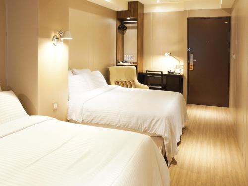 a hotel room with two beds and a desk at Hotel Relax I in Taipei