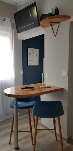 drewniany stół z dwoma niebieskimi krzesłami i telewizorem w obiekcie Agréable petite maison avec jardin et parking w mieście Chamvres