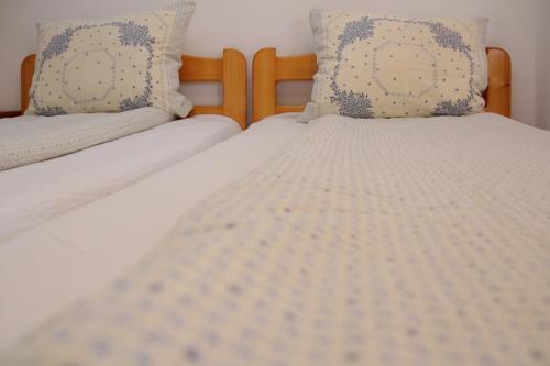 two beds with white sheets and blue pillows at Pensiunea Patakparti in Praid