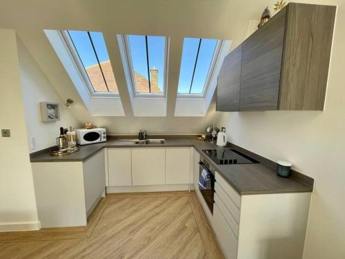 a kitchen with white cabinets and a skylight at Salt Yard Cottage No 1 in Whitstable