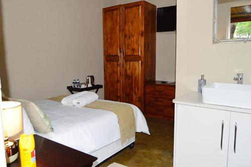 ein Schlafzimmer mit einem weißen Bett und einem Waschbecken in der Unterkunft Pan African Lodge & Safari in Marloth Park