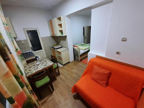 a living room with an orange couch and a kitchen at Smeštaj Milenković in Soko Banja