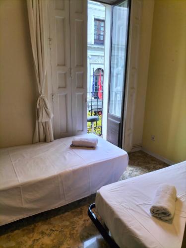 2 camas en una habitación con ventana en Santo Domingo Rooms en Madrid
