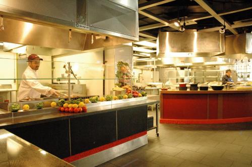 a kitchen with a chef preparing food in a kitchen at University of Toronto - New College Residence - Wilson Hall Residence in Toronto