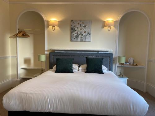 a bedroom with a large white bed with two green pillows at Ardross Glencairn in Inverness