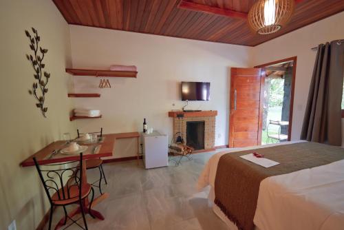 a bedroom with a bed and a desk and a fireplace at Verde da Mantiqueira Chalés in Visconde De Maua