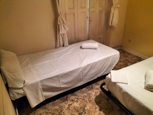 two beds in a room with white sheets at Santo Domingo Rooms in Madrid