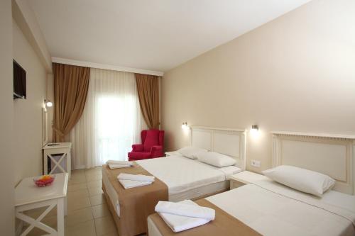 a hotel room with two beds and a red chair at Summer Garden Suites Beach Hotel in Bitez