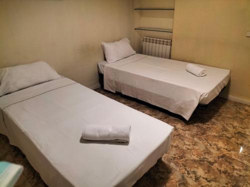 Dos camas en una habitación pequeña con toallas. en Santo Domingo Rooms en Madrid