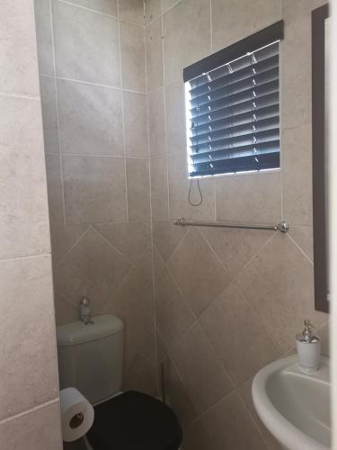 a bathroom with a toilet and a sink and a window at Klyne Jiweel Guesthouse in Pretoria