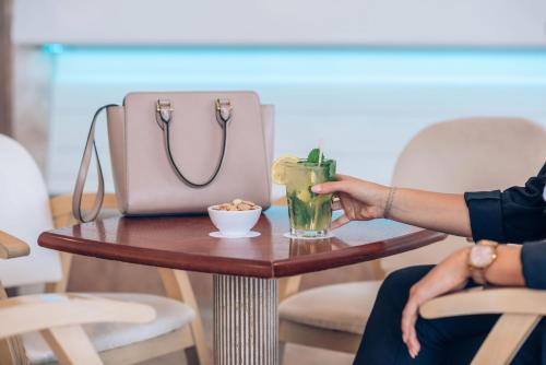 a woman is sitting on a table with a drink on a table sidx sidx at Iberostar Waves Las Dalias All Inclusive in Adeje