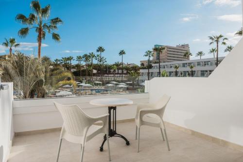 a table and chairs on a balcony with palm trees at Iberostar Waves Las Dalias All Inclusive in Adeje