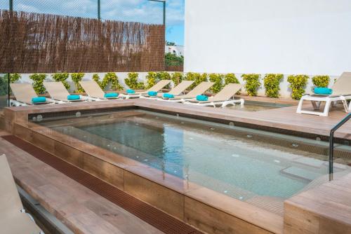a swimming pool with chaise lounge chairs next to a building at Iberostar Waves Las Dalias All Inclusive in Adeje