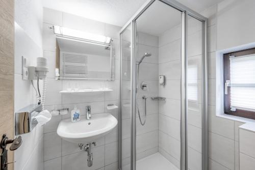 a white bathroom with a shower and a sink at Peater's Hoamat in Sölden