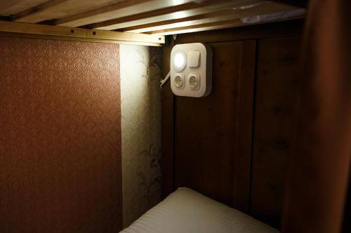 a small room with a bed and a light on the wall at Sweet Home Hostel in Chernivtsi