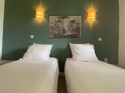two beds in a room with two lights on the wall at La Maison in Les Trois-Îlets