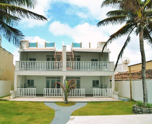 une maison avec des palmiers devant elle dans l'établissement Apartamento Duplex beira Mar, à Nísia Floresta