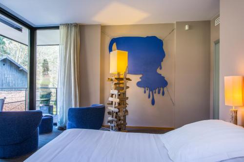 a bedroom with a bed and two blue chairs at Restaurant Hôtel L'Arnsbourg in Baerenthal