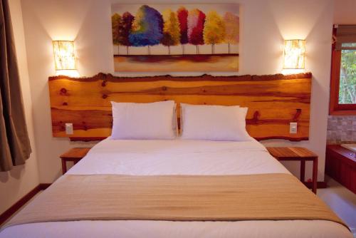 a bedroom with a large white bed with two lamps at Verde da Mantiqueira Chalés in Visconde De Maua