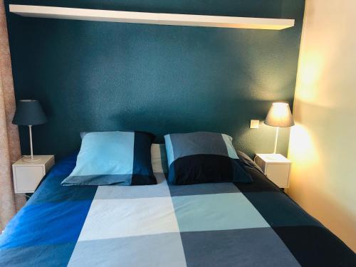 1 dormitorio con 1 cama azul y blanca y 2 almohadas en Lacanau Ocean : Maison de vacances dans la Pinede, en Lacanau