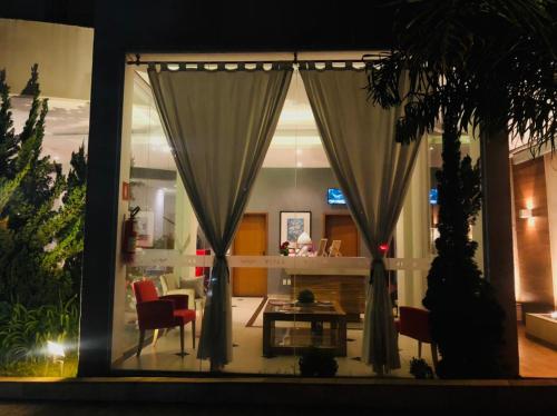 een woonkamer met gordijnen en een tafel bij Vivas Hotel e Casa in Monte Sião