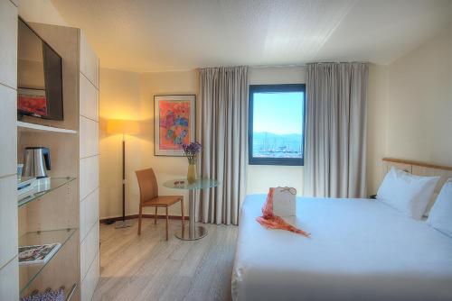 a hotel room with a bed and a table and a window at Mercure Ajaccio in Ajaccio