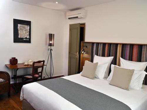 アルジェレス・シュル・メールにあるロスタルのベッド、デスク、椅子が備わるホテルルームです。