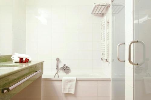 a white bathroom with a shower and a sink at The Gerald's Hotel in Rădăuţi