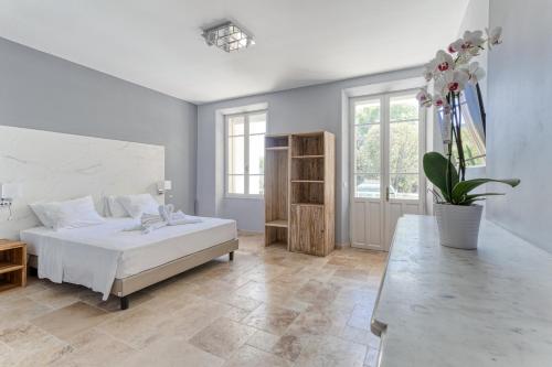 a bedroom with a white bed and a large window at DOMAINE DE LA NERTHE- HOTEL PROVENCE MEDITERRANEE in Gignac-la-Nerthe
