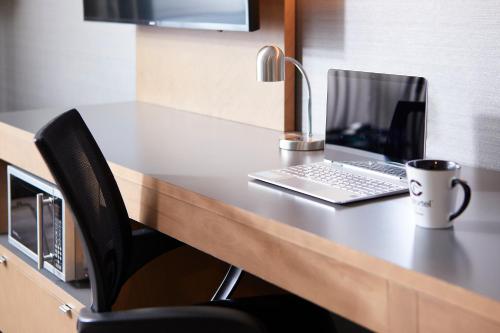 a desk with a laptop and a coffee mug on it at Hôtel Cofortel in Quebec City