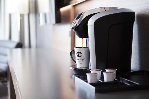 a coffee machine sitting on a counter with two cups at Hôtel Cofortel in Quebec City