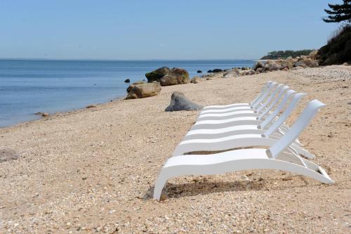 a white chair sitting on a beach near the water at The Cliffside Resort Condominiums in Greenport