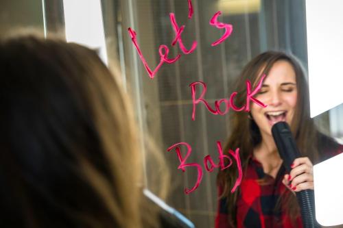 a woman singing into a microphone in front of a mirror at ibis Rueil-Malmaison Centre in Rueil-Malmaison