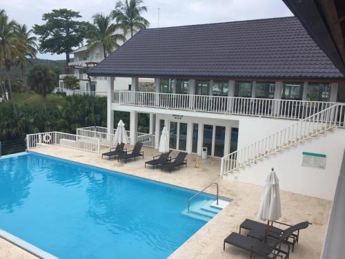 a pool with chairs and umbrellas in front of a building at Vista Mare Samana The Best View!! in Santa Bárbara de Samaná
