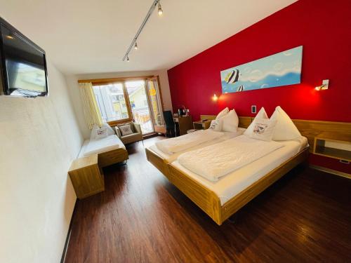 a bedroom with two beds and a red wall at Hotel Toscana in Interlaken