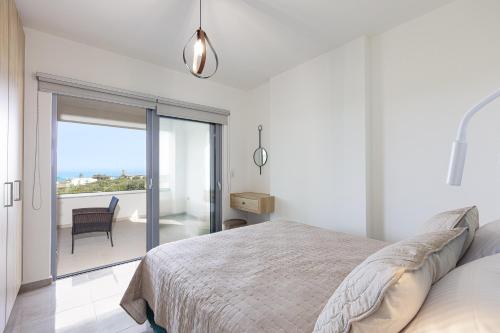 a white bedroom with a bed and a balcony at Blue Aura Villa, elegance & calm living, By ThinkVilla in Magnisía