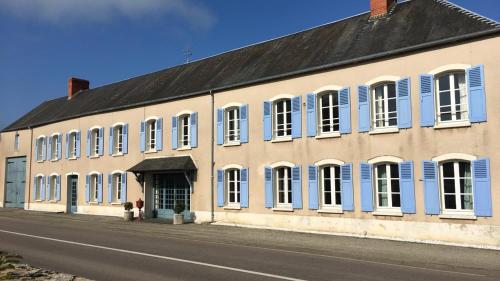 a large building with blue shutters on a street at Maison de 7 chambres avec vue sur le lac jardin clos et wifi a Le Dezert in Montmartin-en-Graignes